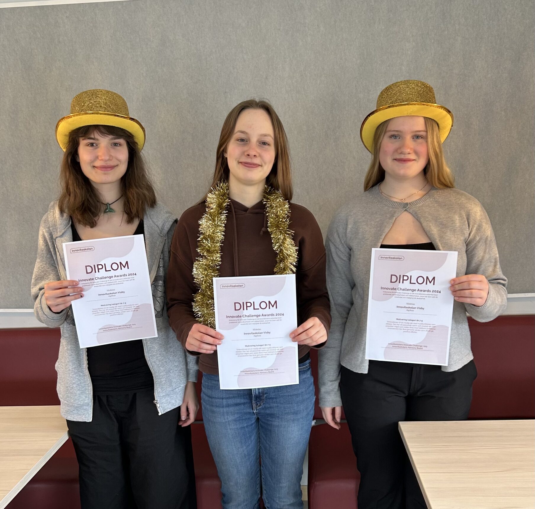 Tre glada tjejer som vunnit Innovate Challenge står med guldhattar och håller i varsitt diplom.