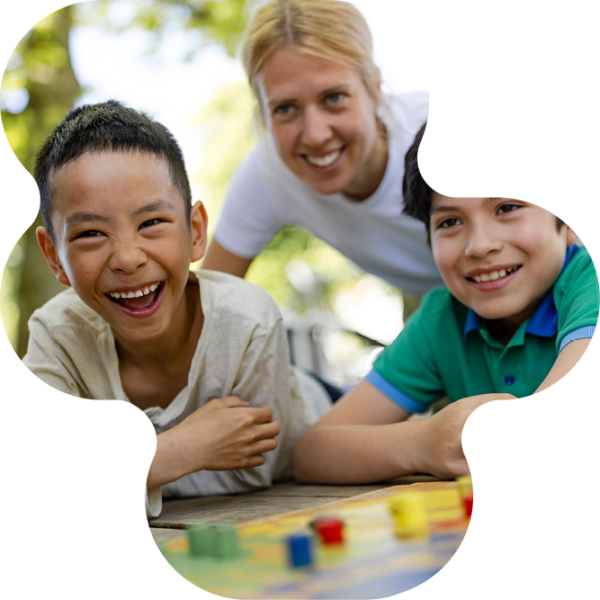 Två glada elever och en pedagog spelar fia med knuff utomhus.