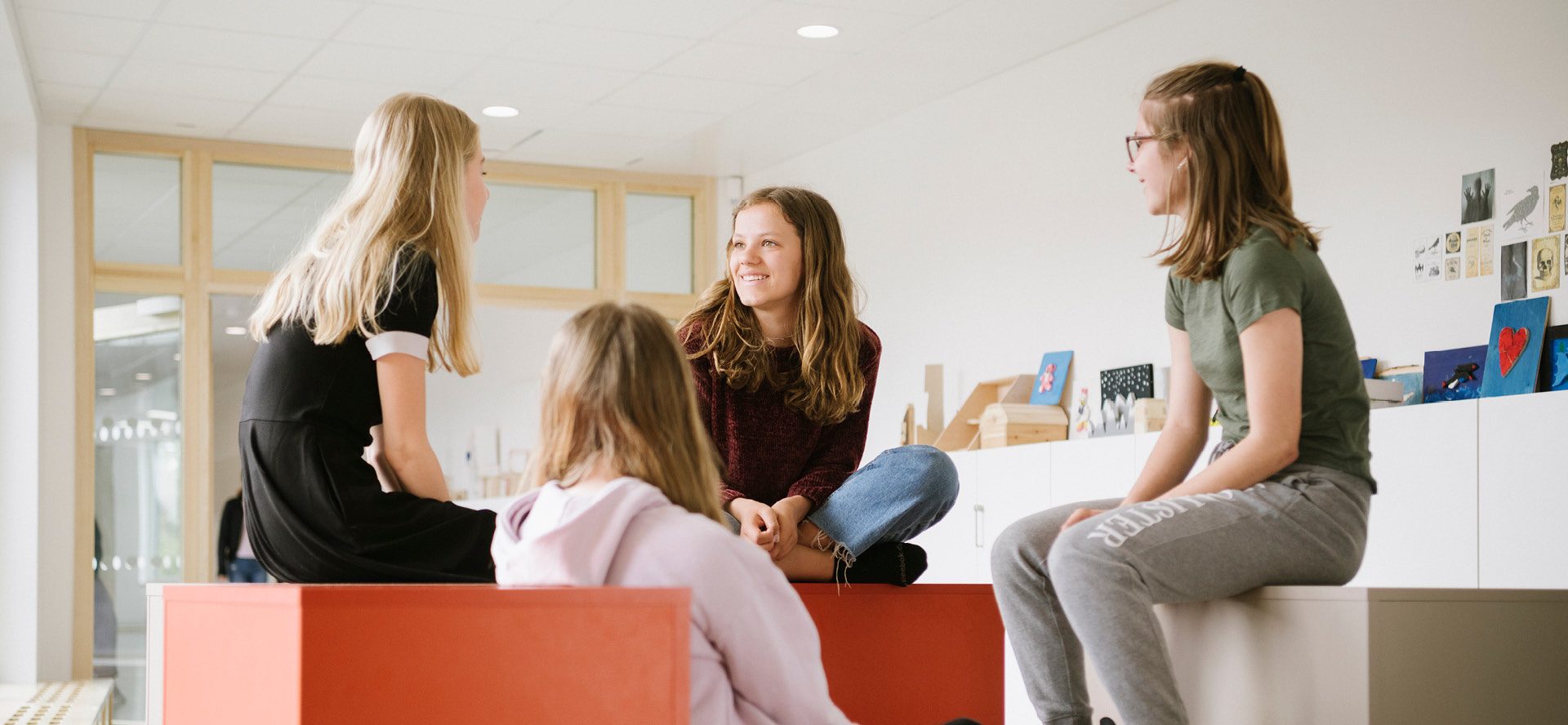 Fyra elever i högstadiet som pratar med varandra i en ljus skolmiljö