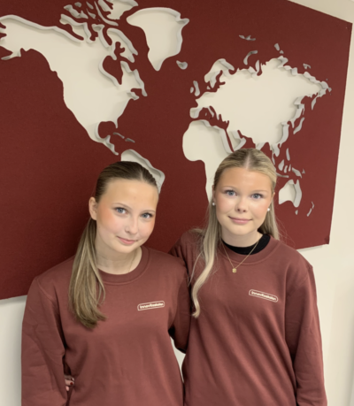Två elever står med Innovitaskolans tröja på sig framför en världskarta som hänger på väggen. De jobbar för elevdemokrati och elevinflytande genom att vara delaktiga i Innovitarådet.