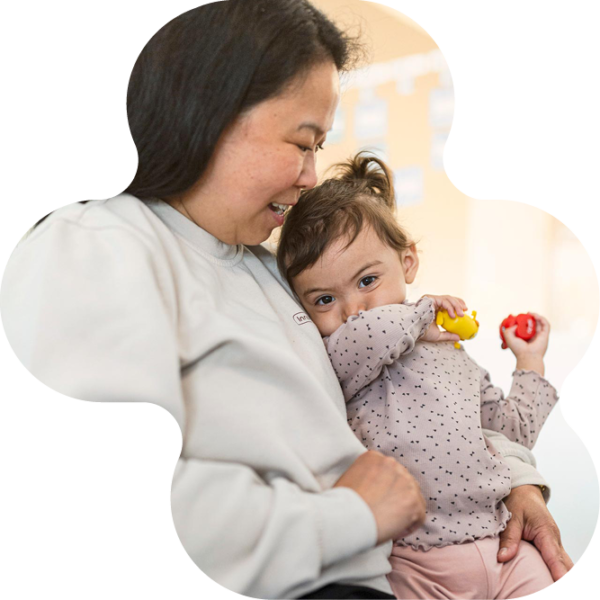 Pedagog sitter med litet barn på förskolan i knäet.