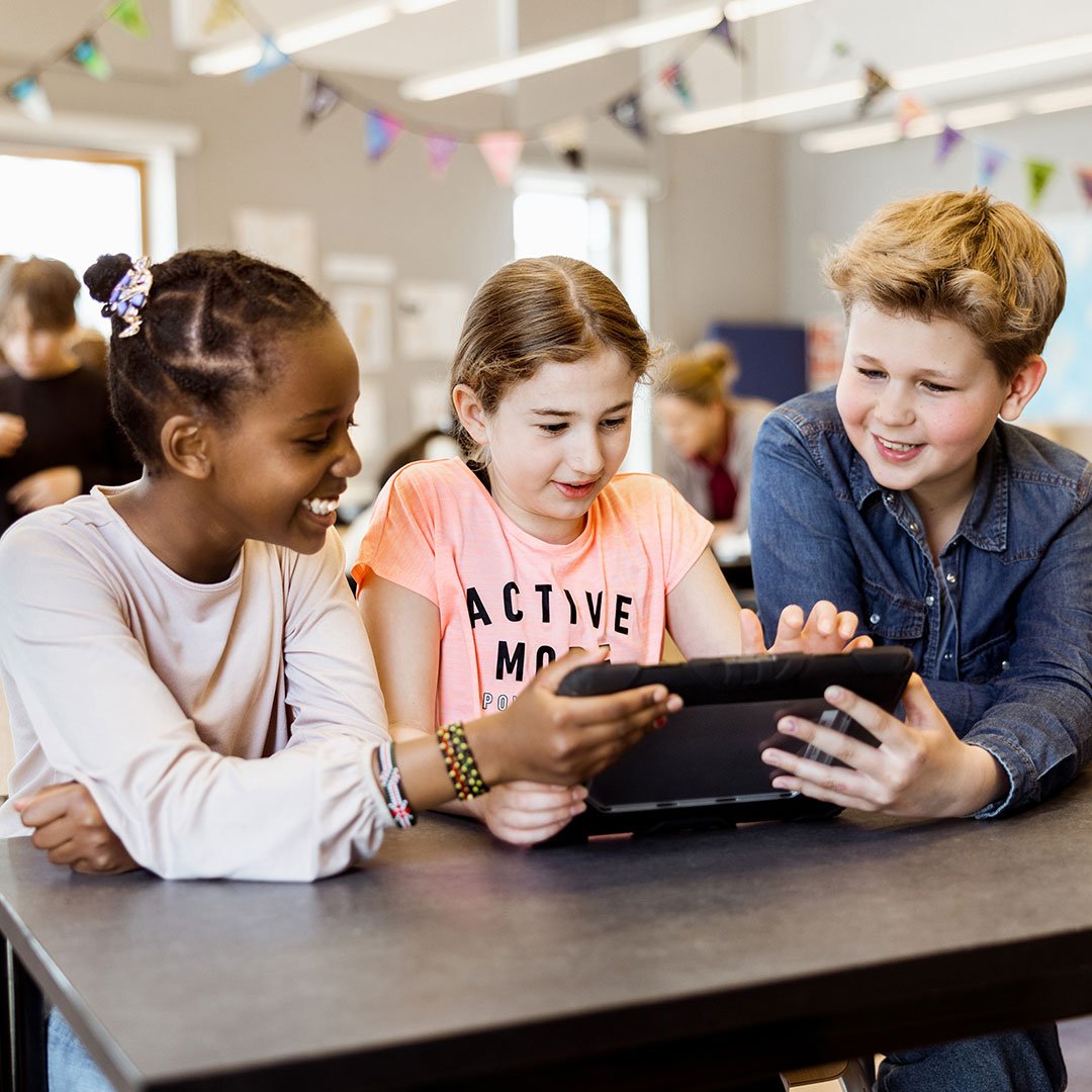 Tre elever på Innovitaskolan jobbar med en läsplatta.