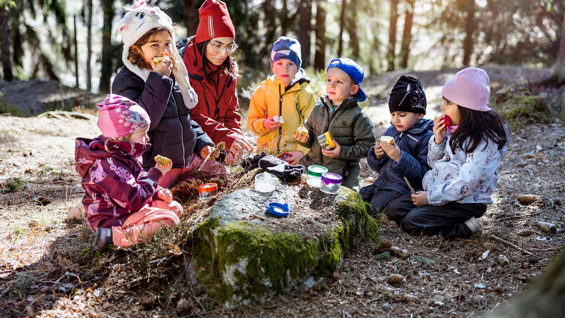 Förskolebarn äter mellanmål ute i naturen.