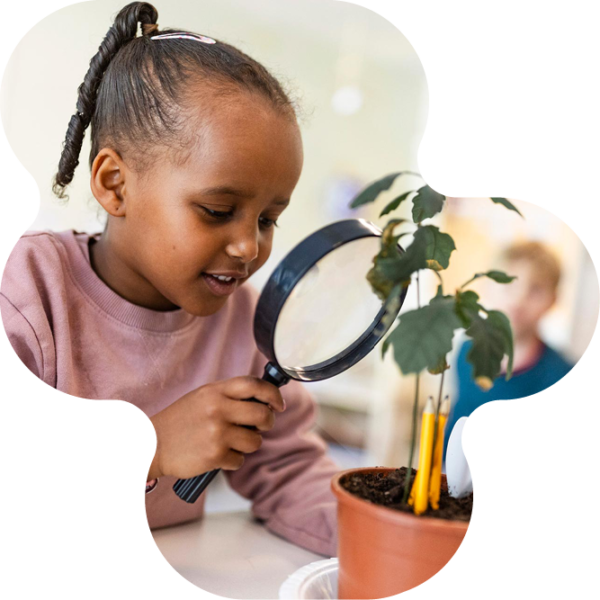 Elev undersöker en växt med ett stort förstoringsglas.