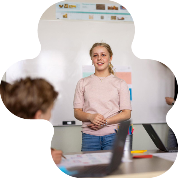 En elev står framme vid tavlan och presenterar sitt arbete för klasskompisarna.