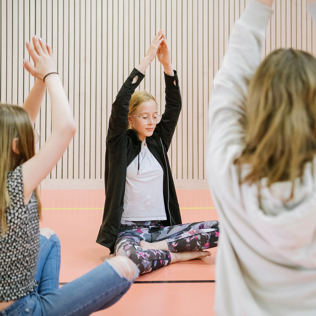 Tre elever i mellanstadiet som tränar yoga på Innovitaskolan.