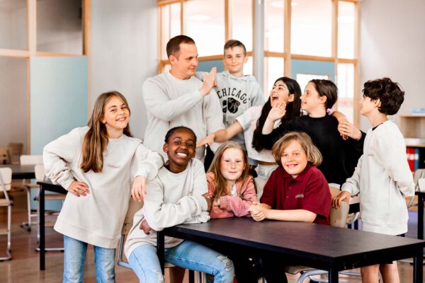 En gruppbild på glada elever och pedagog som ler in i kameran.