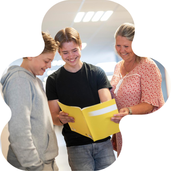 Elever och lärare som tittar i lärobok.