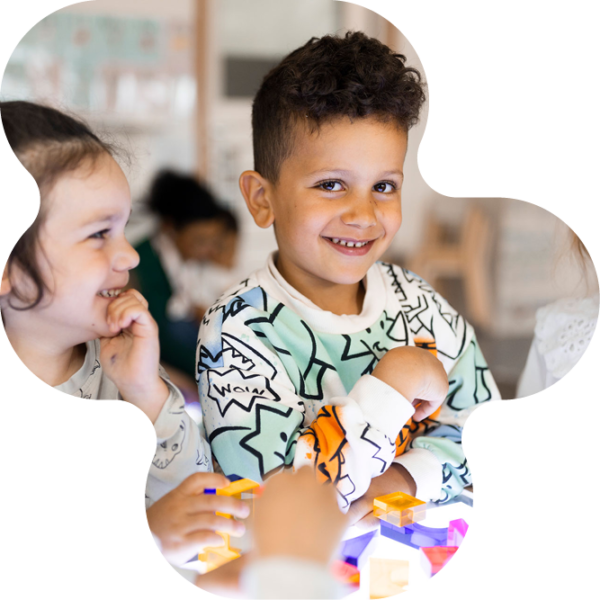 Två barn på förskolan lär tillsammans vid ett lysbord med klossar.