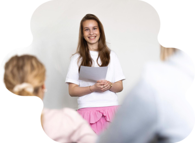 En elev står framme vid tavlan och presenterar något för sina klasskompisar.