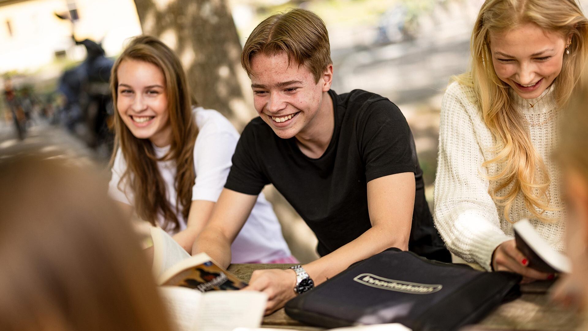 Elever som sitter ute vid bänk.
