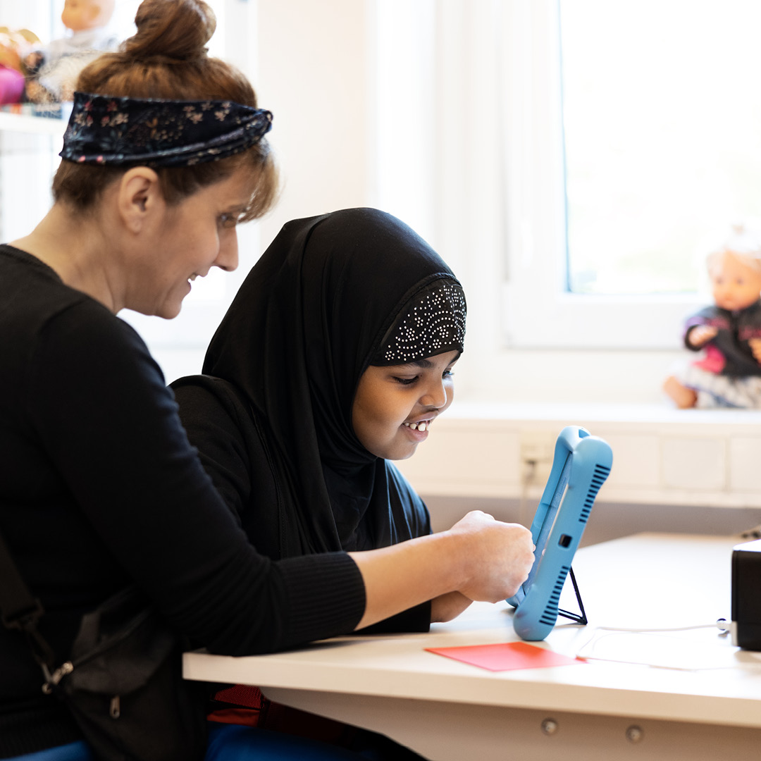 Elev i mellanstadiet och lärare tittar in i en iPad tillsammans på Innovitaskolan Joriel i Älvsjö.